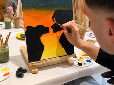 Participante pintando un cuadro de osos al atardecer
