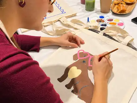 Participante pintando una tote bag con un perro