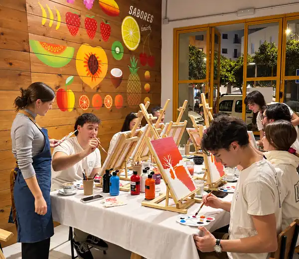 Participantes pintando sus cuadros con la profesora en el taller